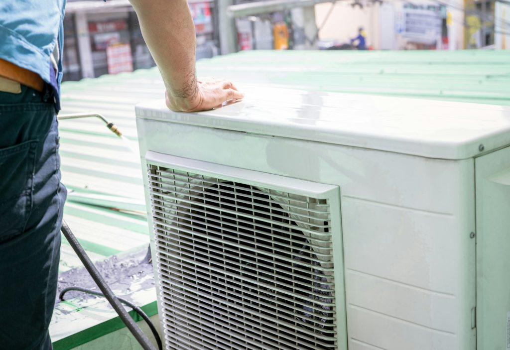 Condensing unit of an air conditioner on blur technician spraying water. Air conditioner cleaning