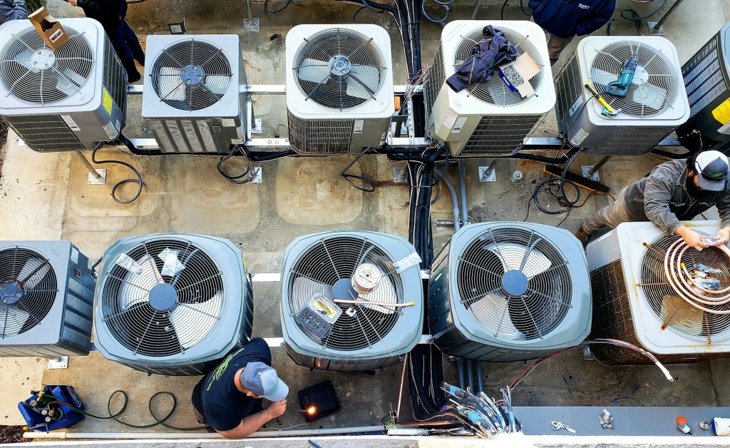 Overhead of utility workers maintaining outside air conditioning HVAC units at a beach condo.